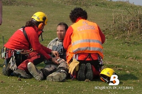 Efectivos del Grupo de Rescate de Bomberos de Asturias prestan asistencia al motorista herido antes de evacuarlo en el helicoptero. Foto: BA