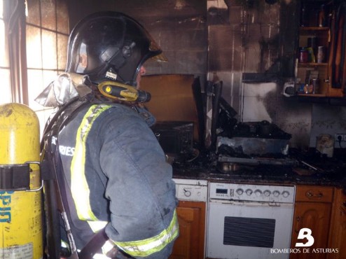 Los bomberos revisan la cocina del piso afectado tras extinguir las llamas que calcinaron la estancia.