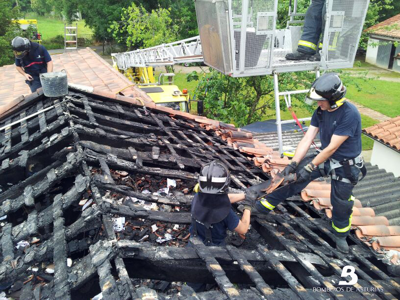 Los bomberos retirando a mano las tejas de la techumbre que qued totalmente calcinada