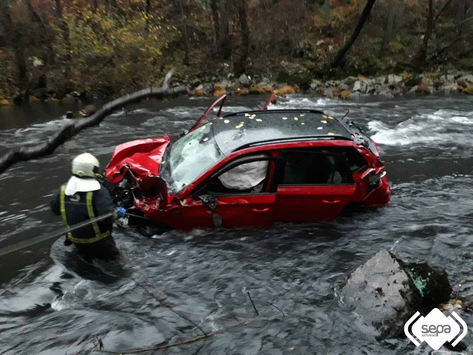 Bomberos con el coche accidentado en Tineo.