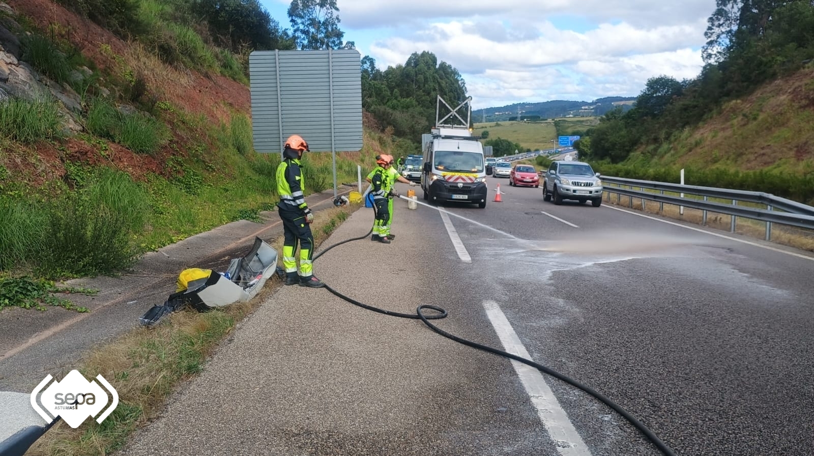 Bomberos retirando y limpiando parte del gasoil fugado de uno de los turismos