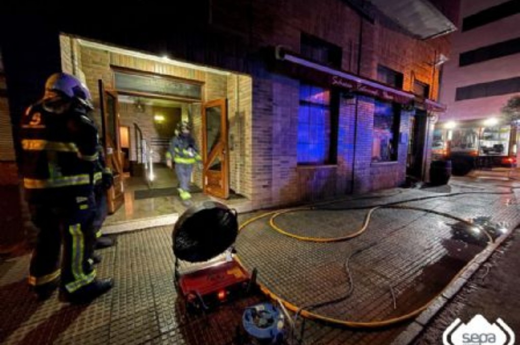 Bomberos revisando el edificio afectado por el humo del incendio de una sidrería en Castrillón.